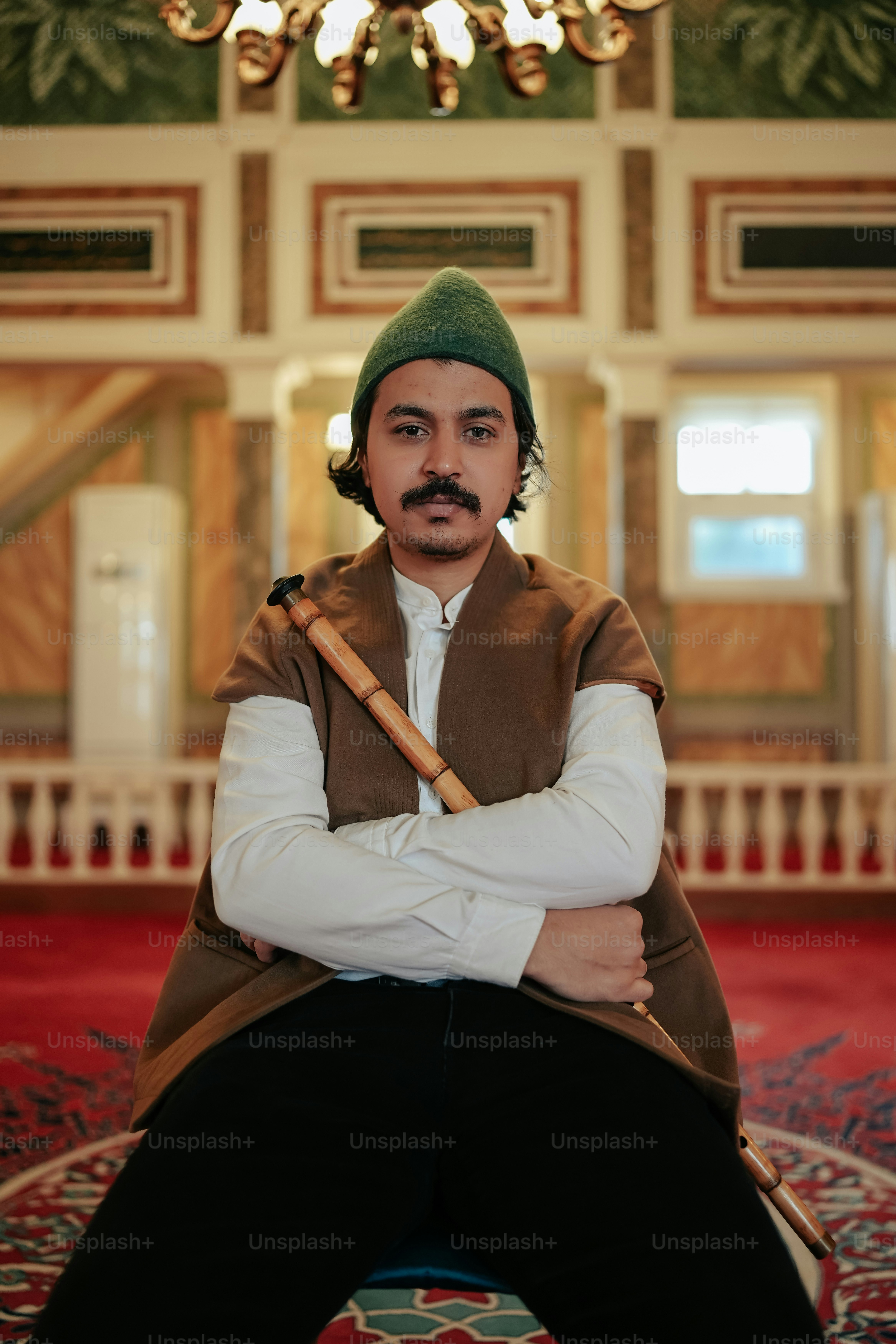 Seorang pria bertopi hijau memegang tongkat bisbol
