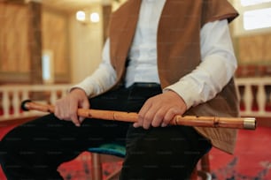 a man sitting on a chair holding a wooden stick
