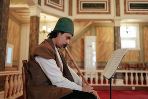 a man sitting in a chair with a pipe in his mouth