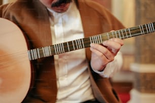 Un hombre sosteniendo una guitarra en su mano derecha