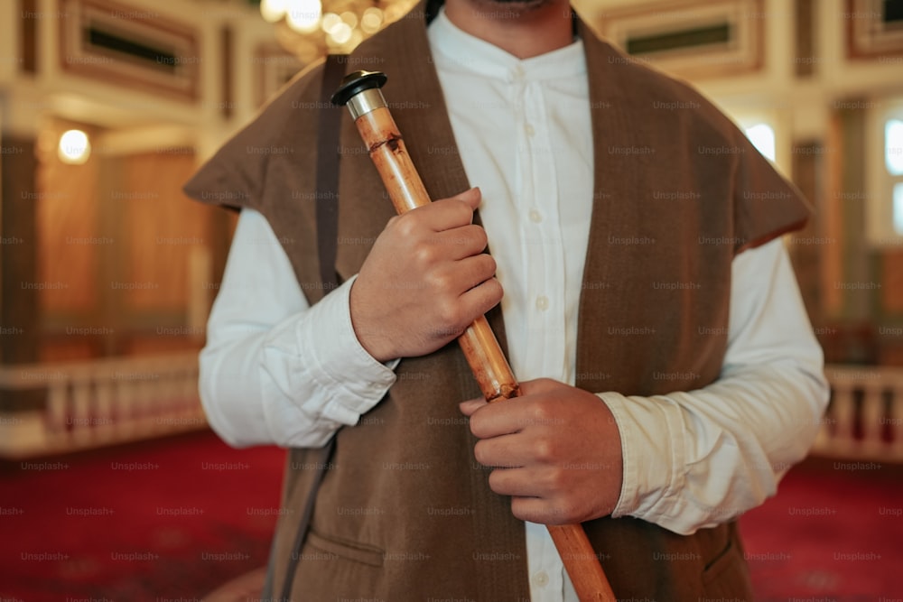 um homem em um colete segurando uma vara de madeira