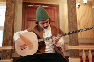 Un uomo con un cappello verde che suona una chitarra