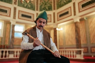 Un uomo con un cappello verde tiene in mano un bastone