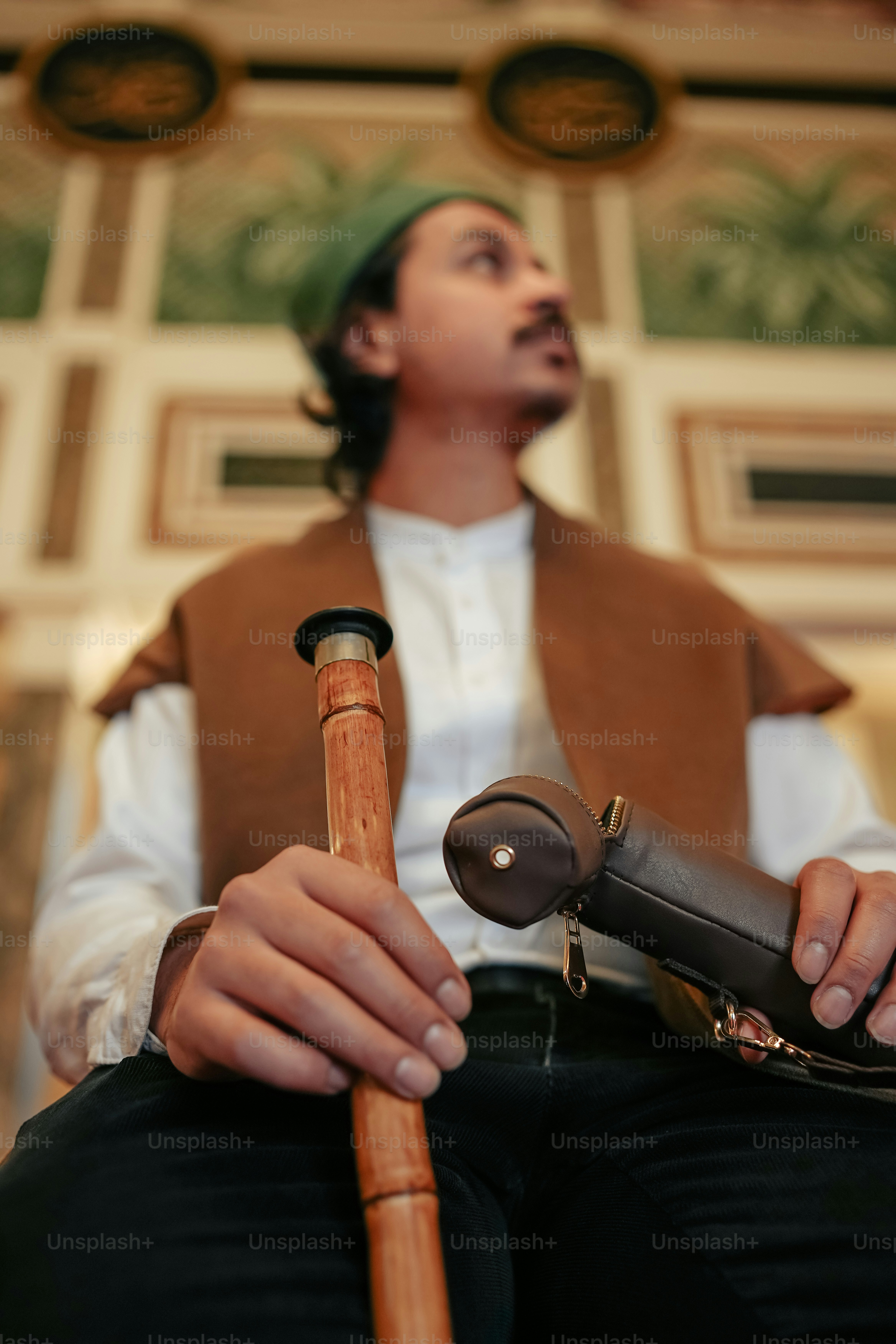a man sitting down holding a wooden stick