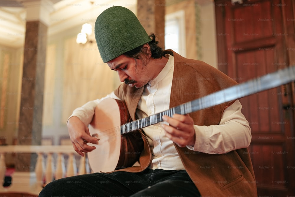 a man in a green hat playing a guitar