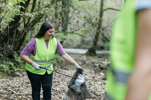 a woman in a yellow vest is holding a trash bag