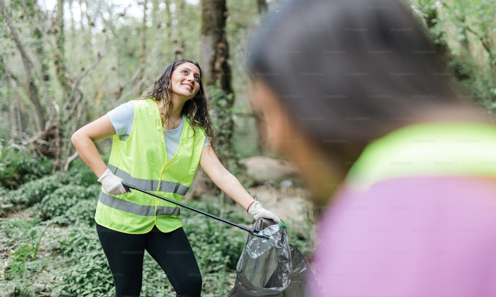 a woman in a safety vest is holding a trash can