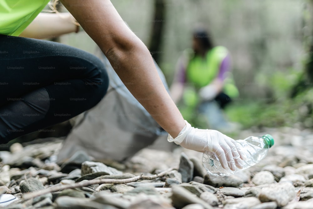 a person picking up a plastic bottle from a pile of rocks