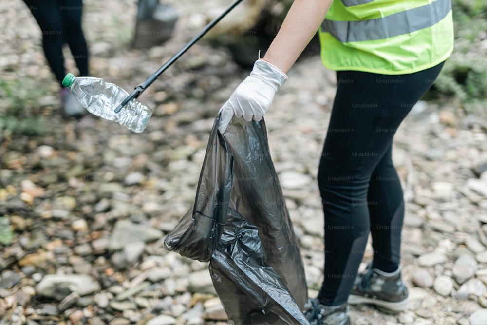 a person holding a trash bag and a shovel