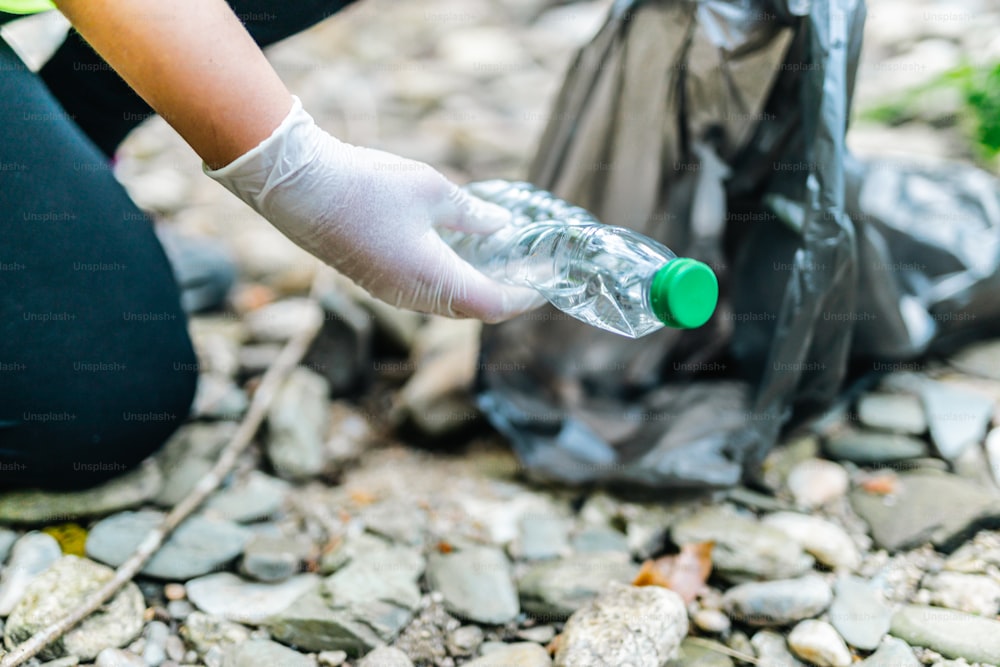 una persona recogiendo una botella de plástico de un bote de basura