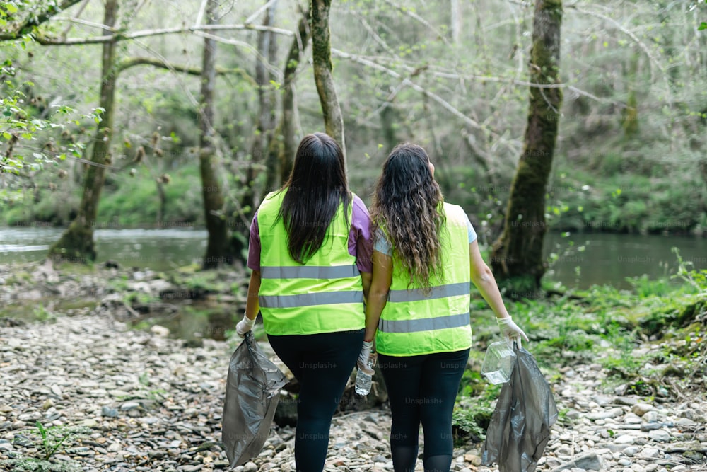two women in yellow vests walking through a forest
