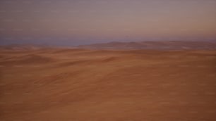 a desert with sand dunes and mountains in the distance