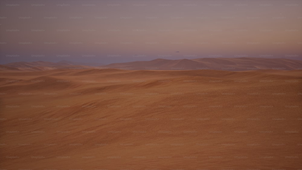 a desert with sand dunes and mountains in the distance