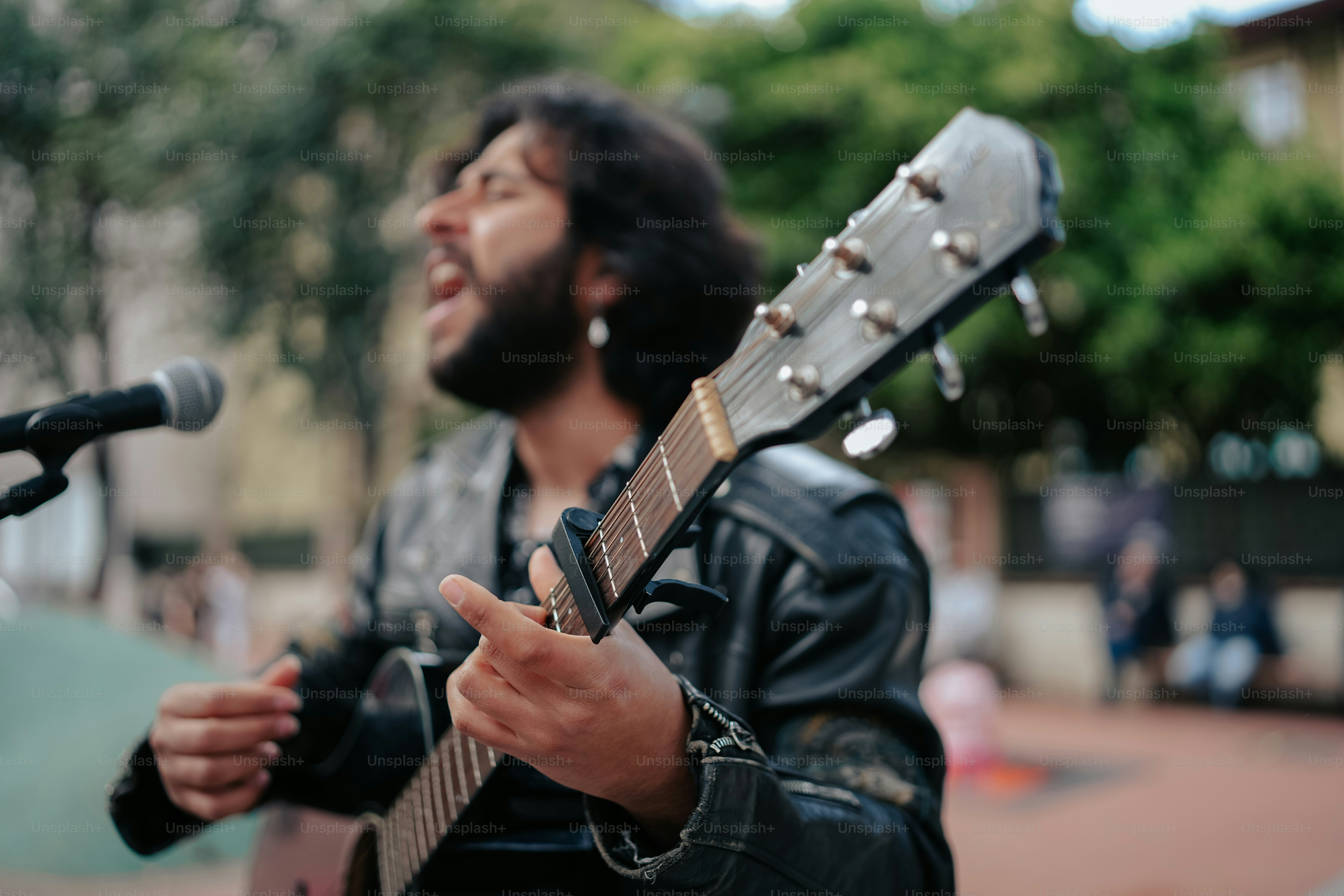a man holding a guitar and singing into a microphone