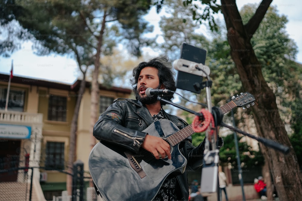 a man playing a guitar in front of a microphone