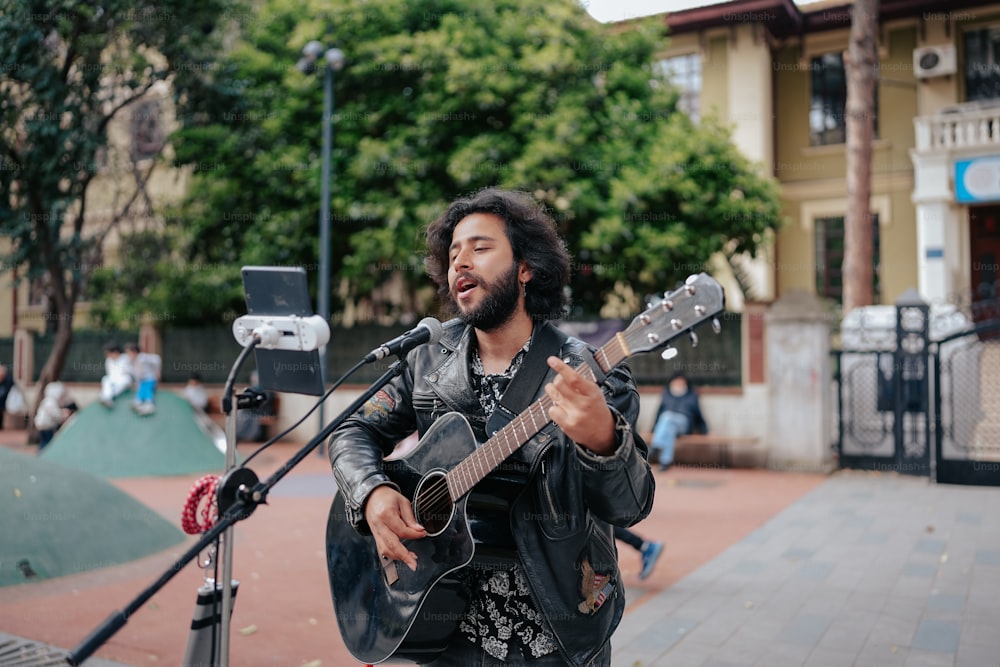 a man playing a guitar in front of a microphone