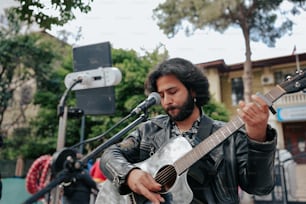 Un uomo che suona una chitarra davanti a un microfono