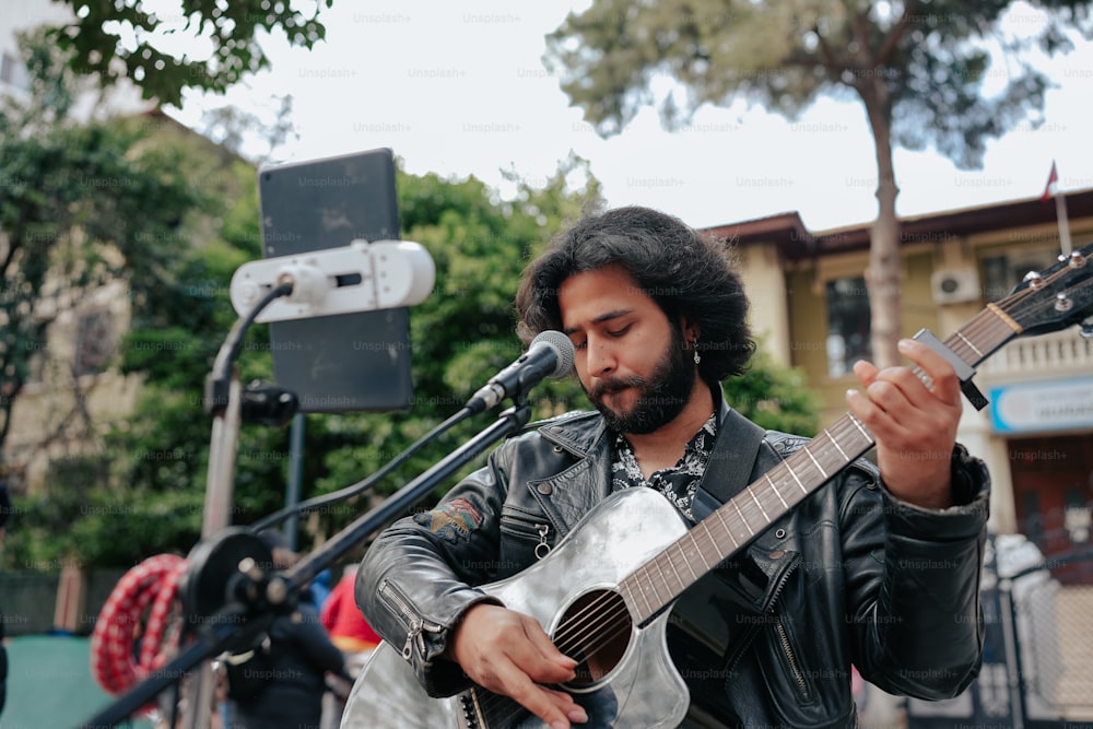 a man playing a guitar in front of a microphone