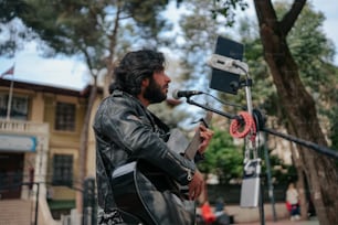 a man playing a guitar in front of a microphone