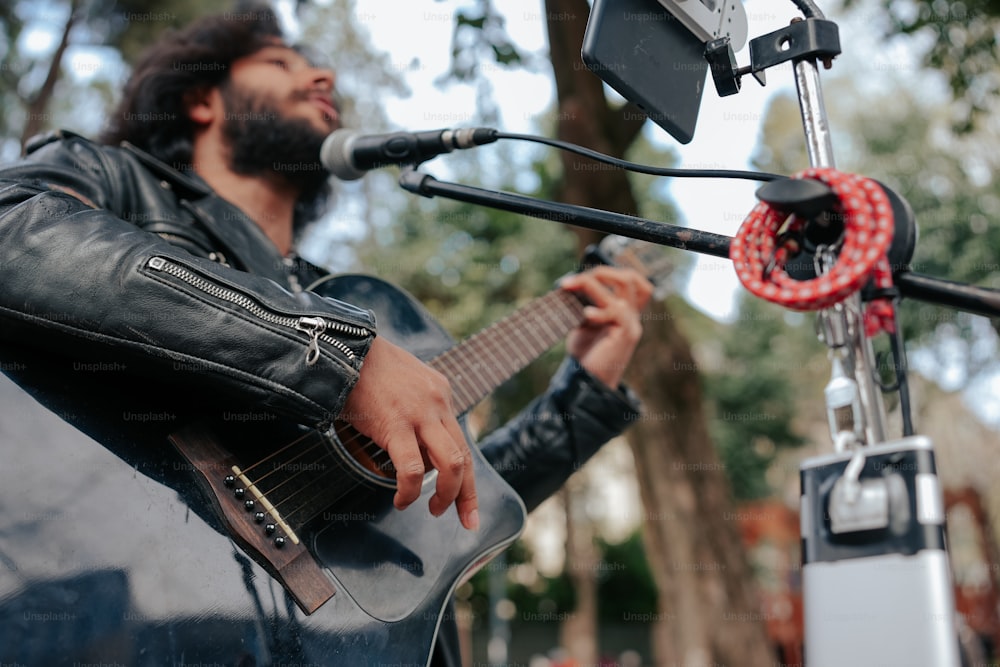 a man playing a guitar in front of a microphone