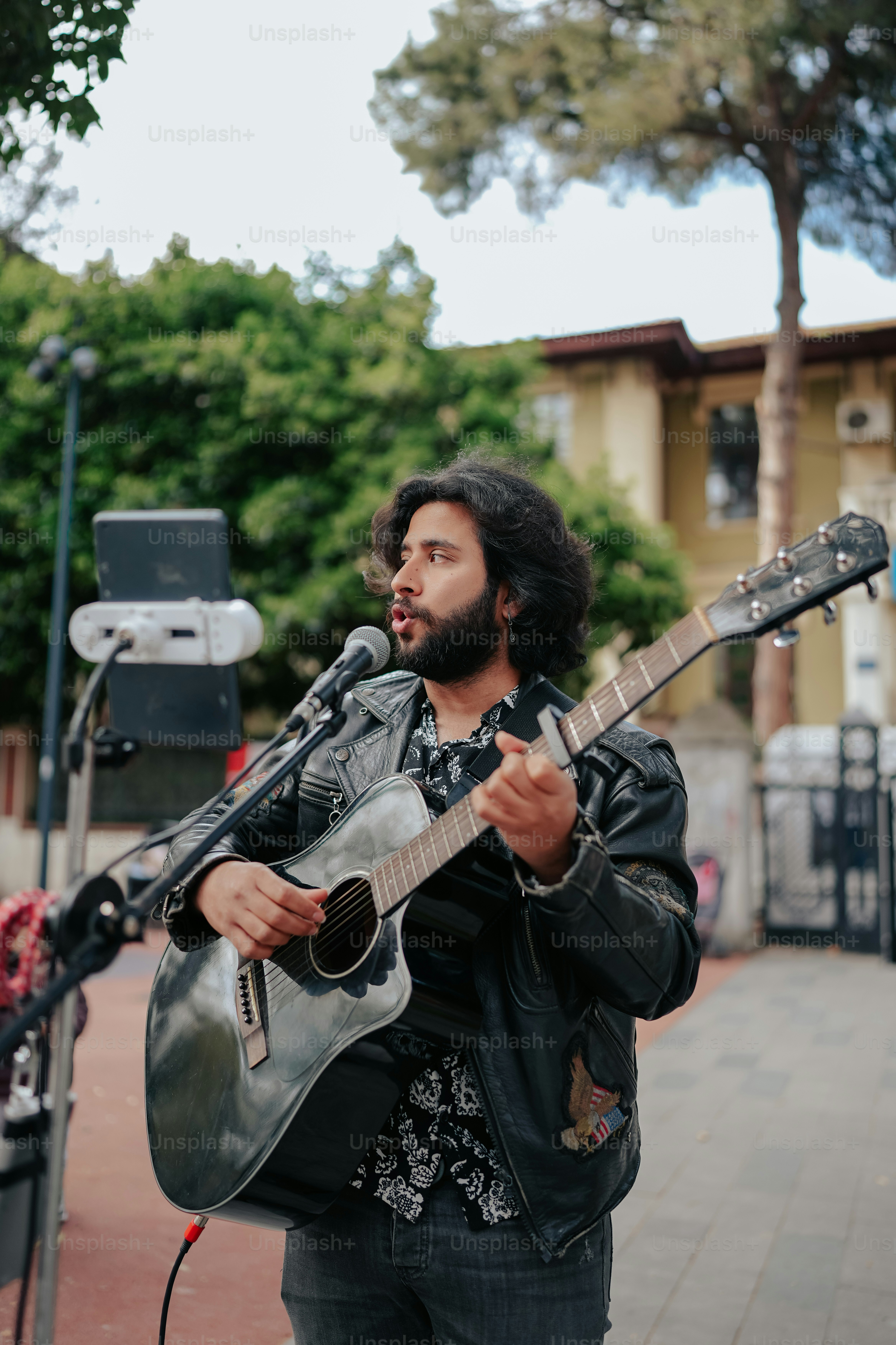 a man playing a guitar while standing on a sidewalk
