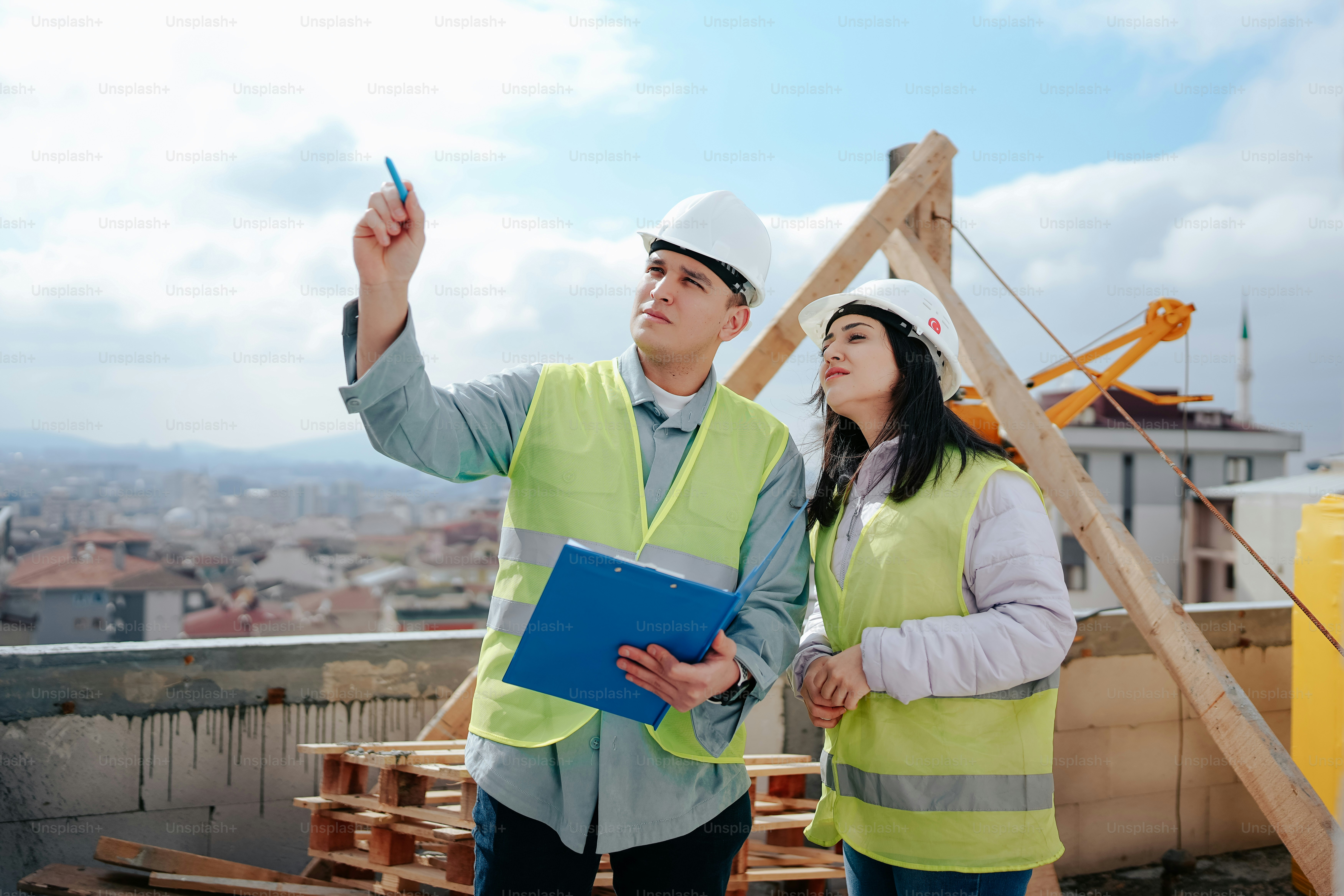 Ein Mann und eine Frau in Warnwesten stehen auf einem Dach