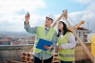a man and woman in safety vests standing on a roof