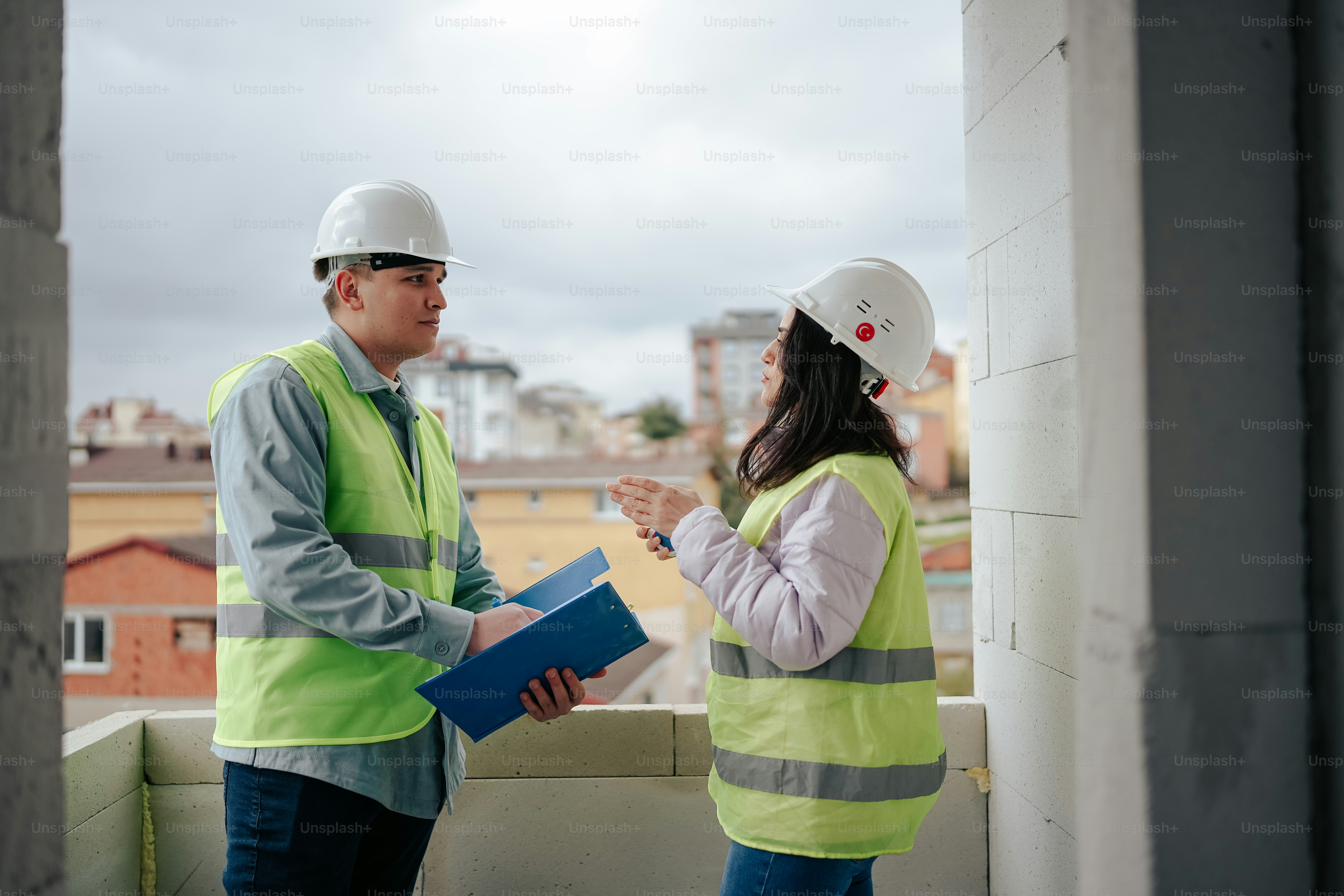 A man and a woman wearing hard hats and safety vests photo – Architect ...