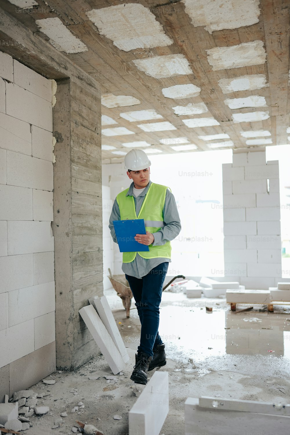 um homem de capacete e colete de segurança em pé em um prédio em construção