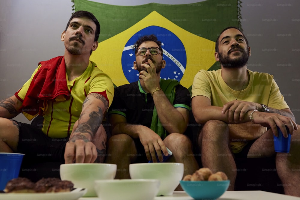 three men sitting on a table with bowls of food