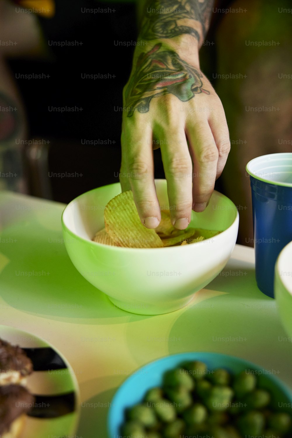 a man with a tattooed arm is dipping a potato into a bowl