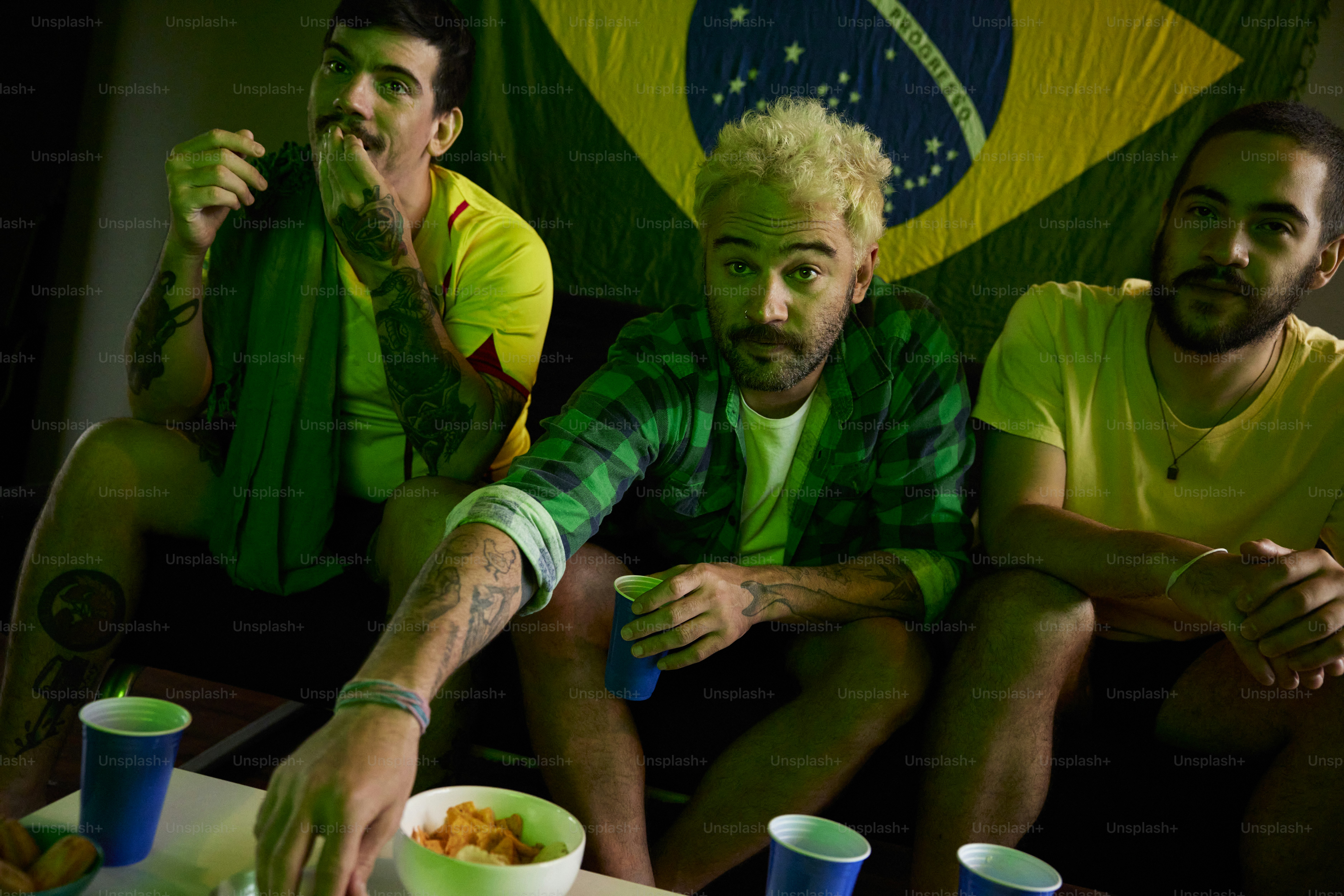 A group of men sitting around a table eating food photo – Football ...
