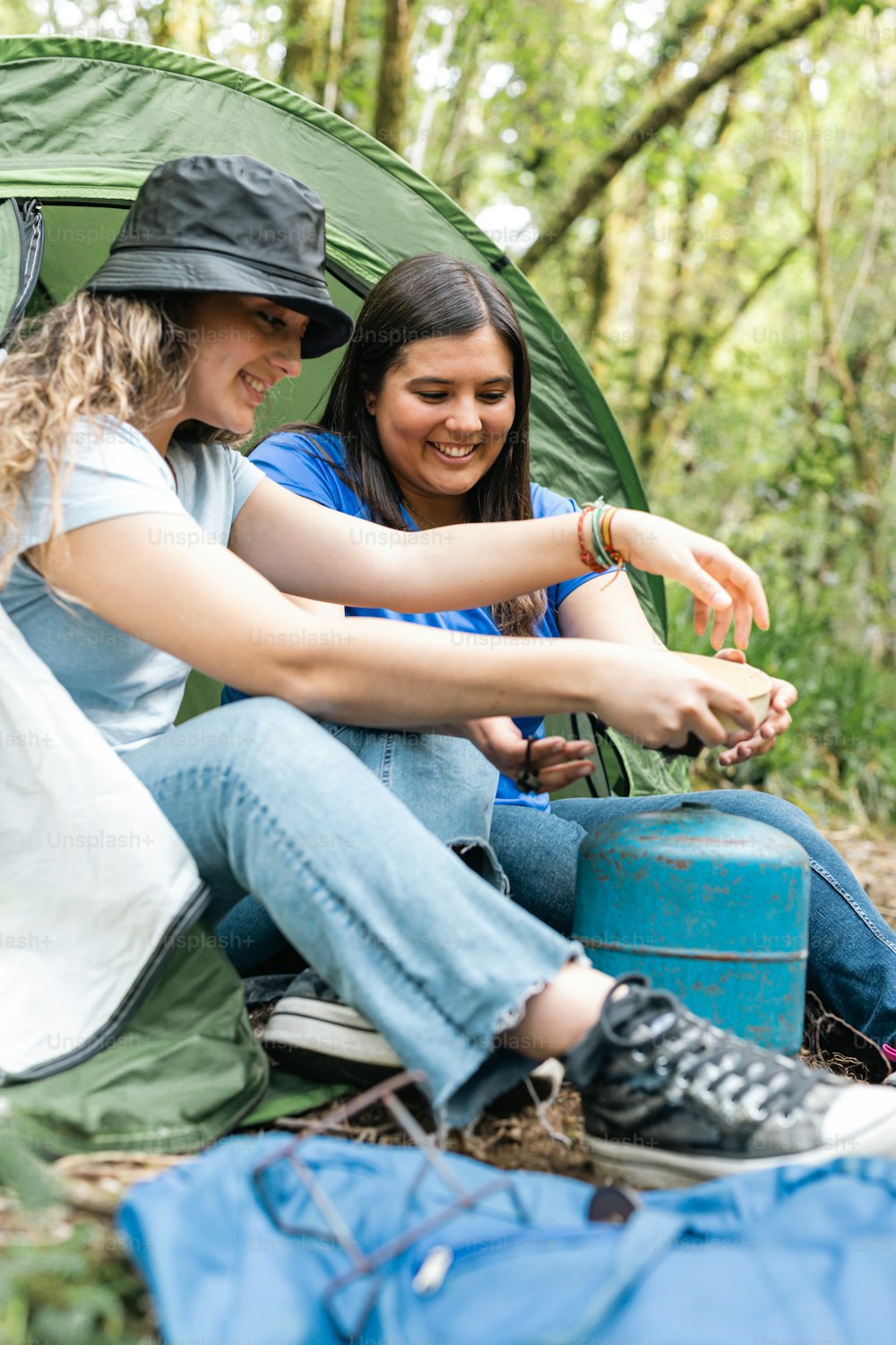 duas mulheres sentadas em uma tenda na floresta
