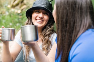 a woman holding a cup and smiling at another woman