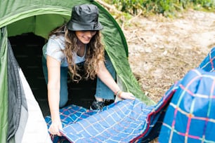 a woman putting a sleeping bag inside of a tent