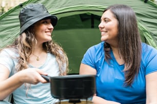 a couple of women sitting next to each other near a tent