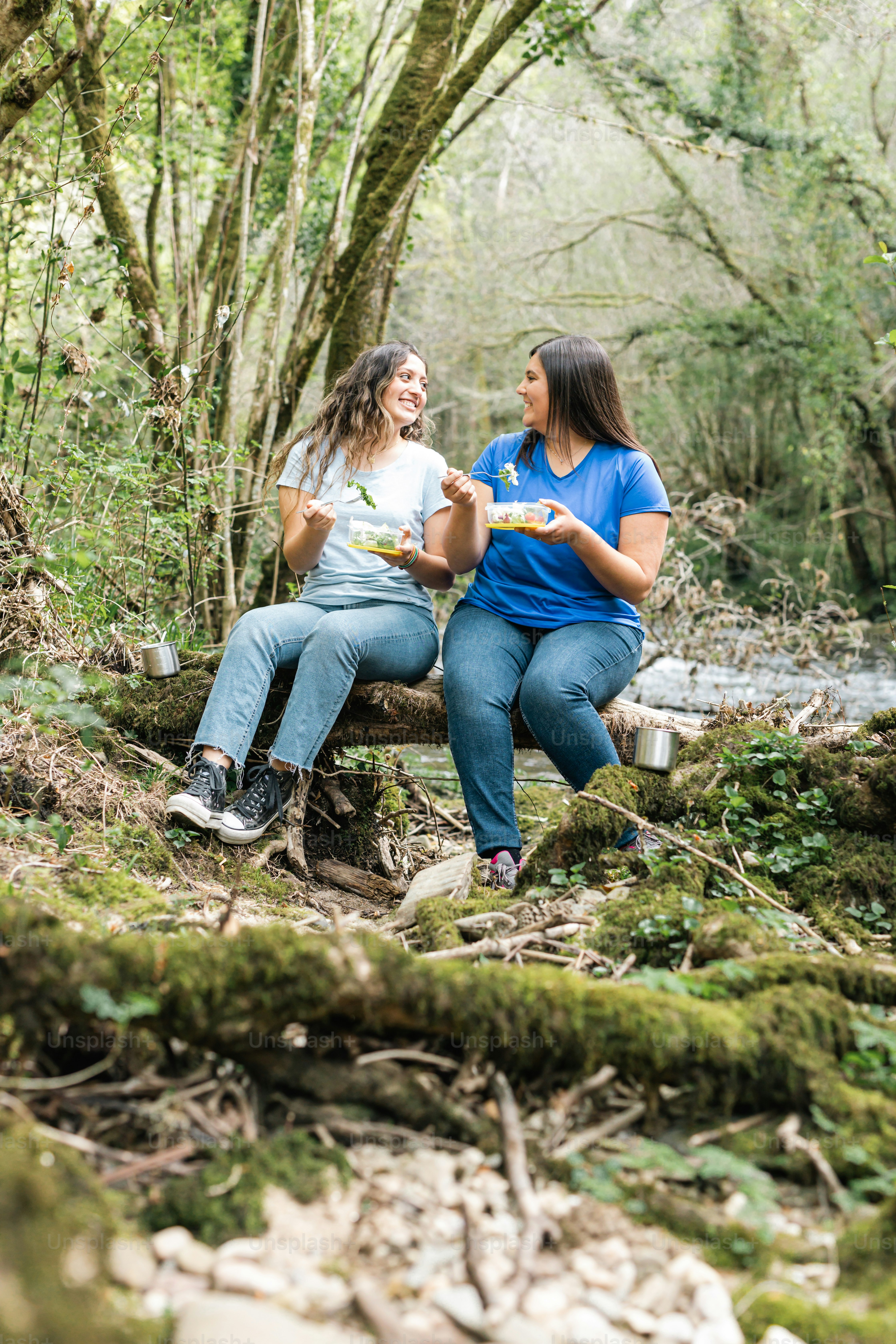 two women sitting on a bench in the woods