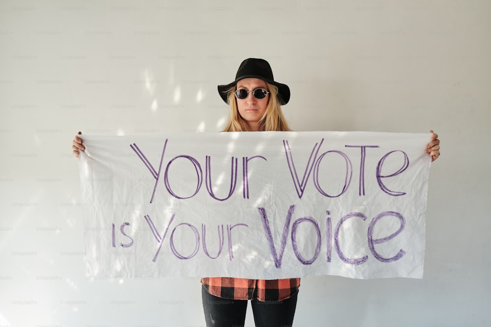 uma mulher segurando uma placa que diz que seu voto é sua voz