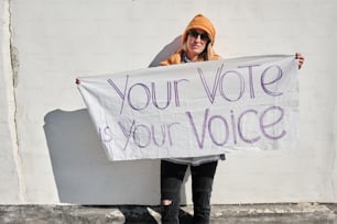 uma mulher segurando uma placa que diz que seu voto é sua voz