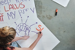 a woman is drawing on a sign with markers