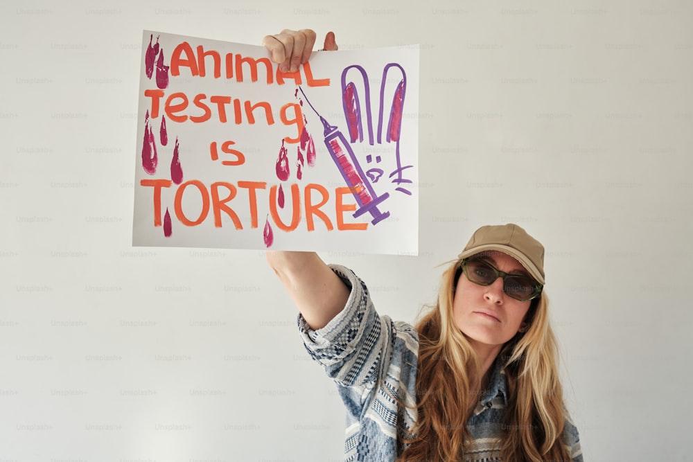 Una mujer sosteniendo un cartel que dice que las pruebas con animales son tortura