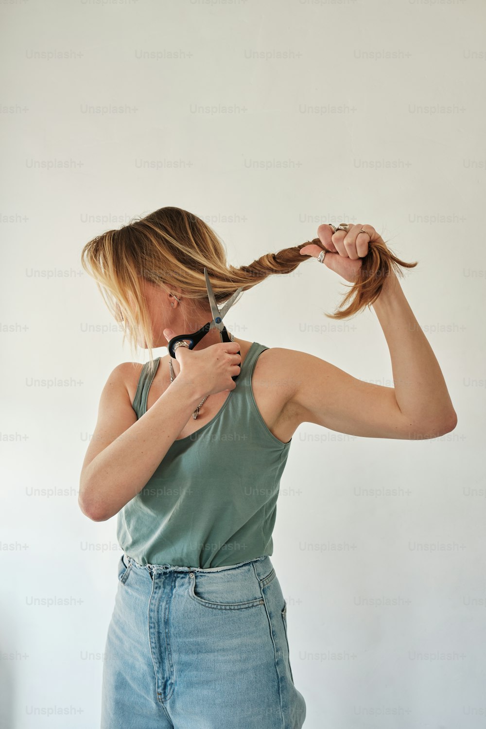 a woman cutting her hair with a pair of scissors