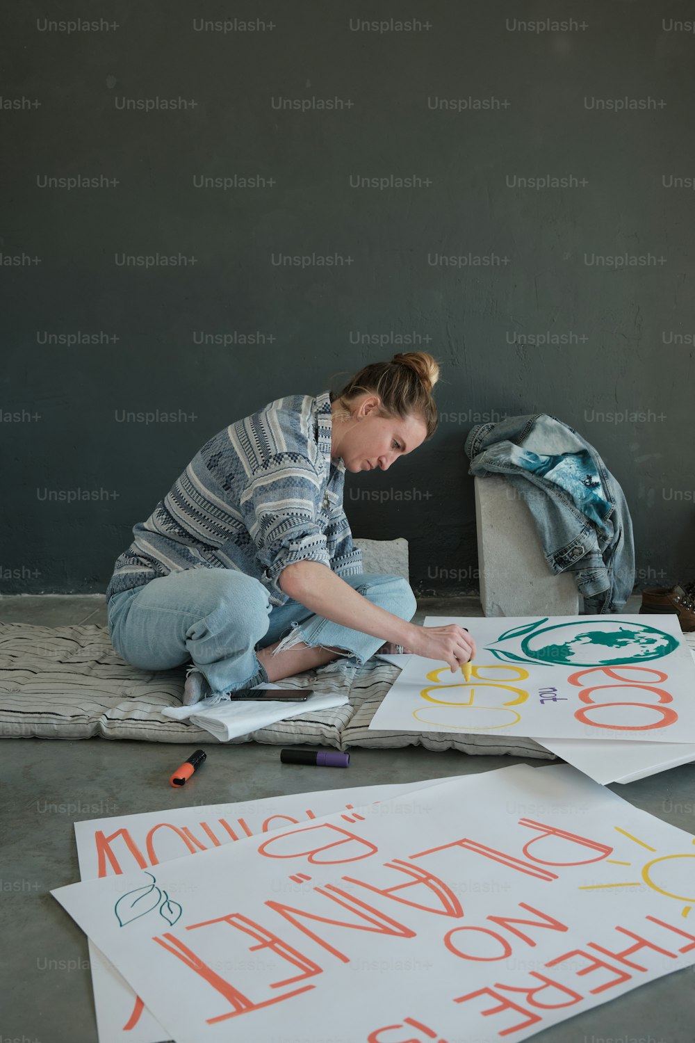 a woman is sitting on the floor drawing letters