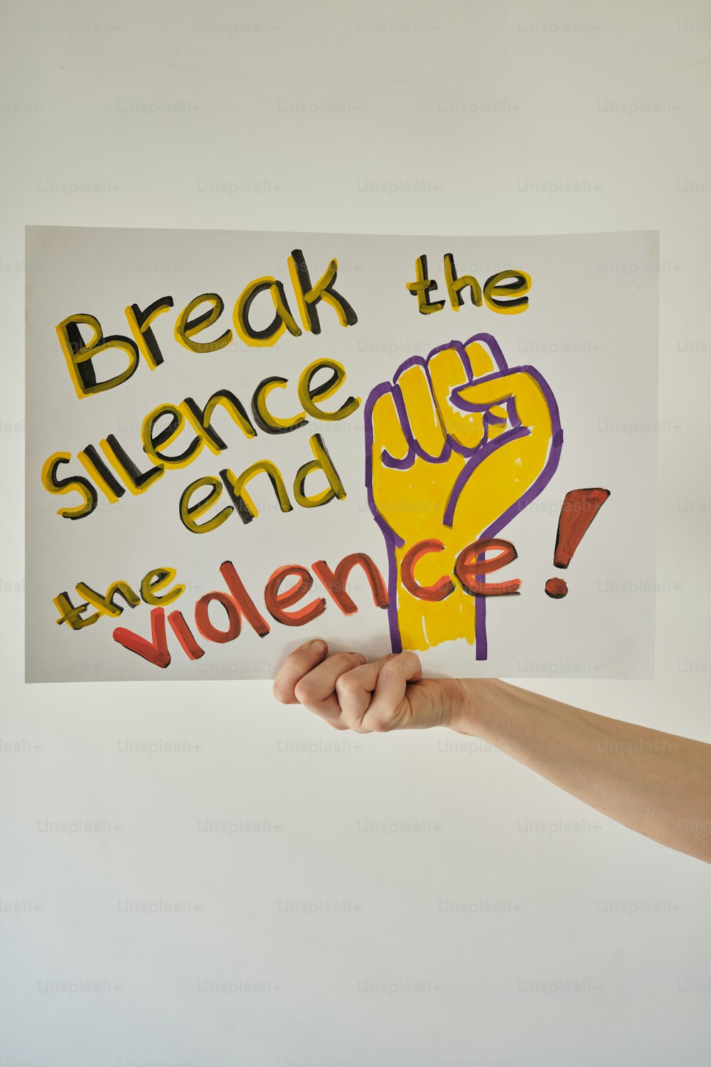 una mano che regge un cartello che dice rompere il silenzio e dare violenza