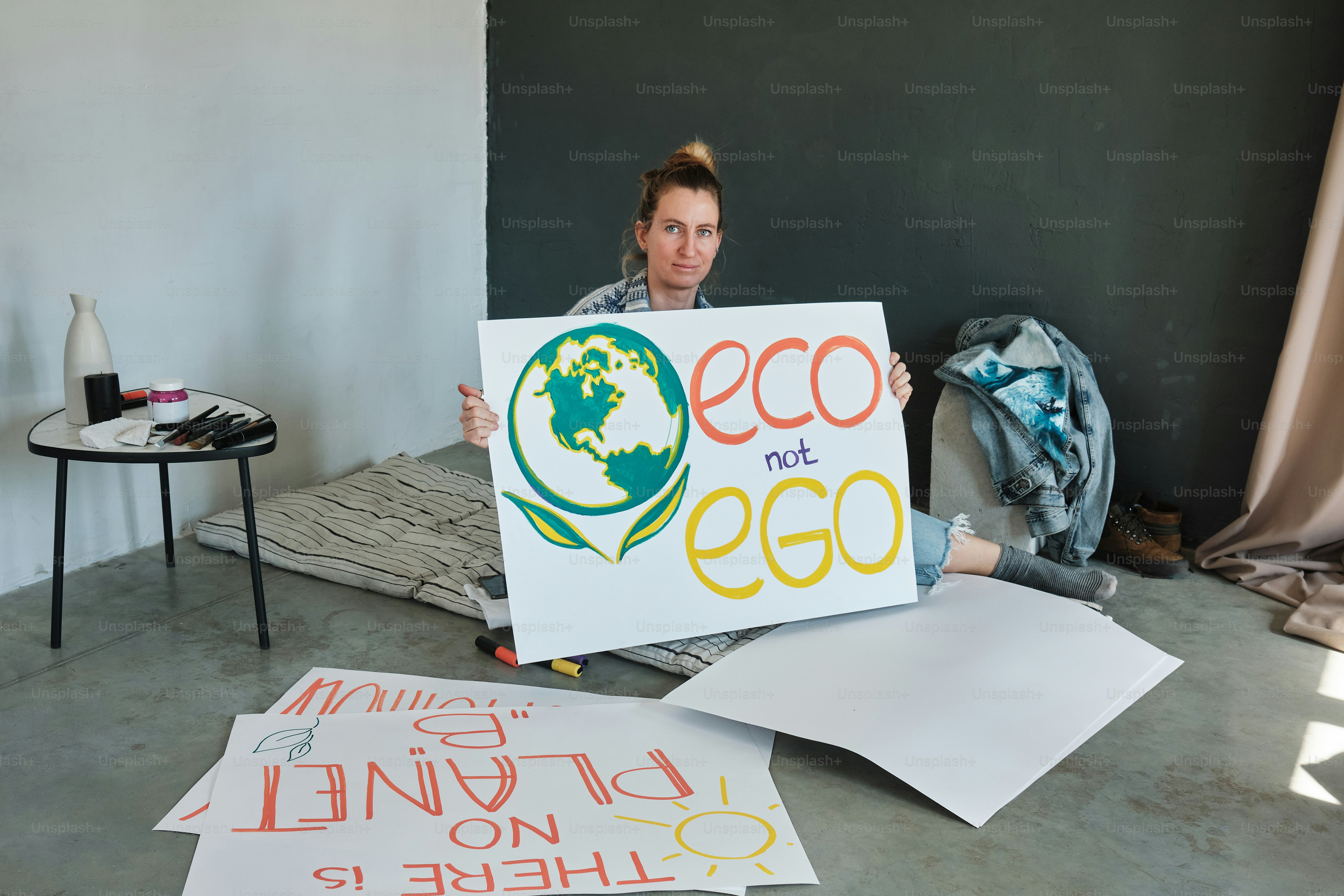 a woman sitting on the floor holding a sign