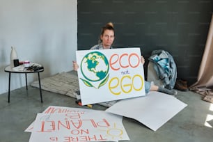a woman sitting on the floor holding a sign