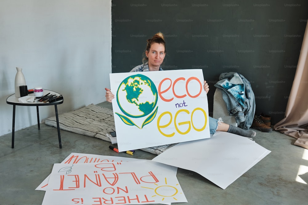 a woman sitting on the floor holding a sign