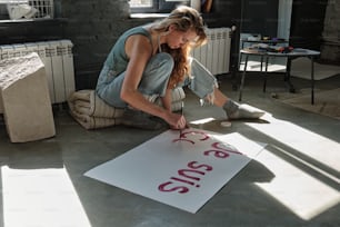 Eine Frau sitzt mit einem Schild auf dem Boden
