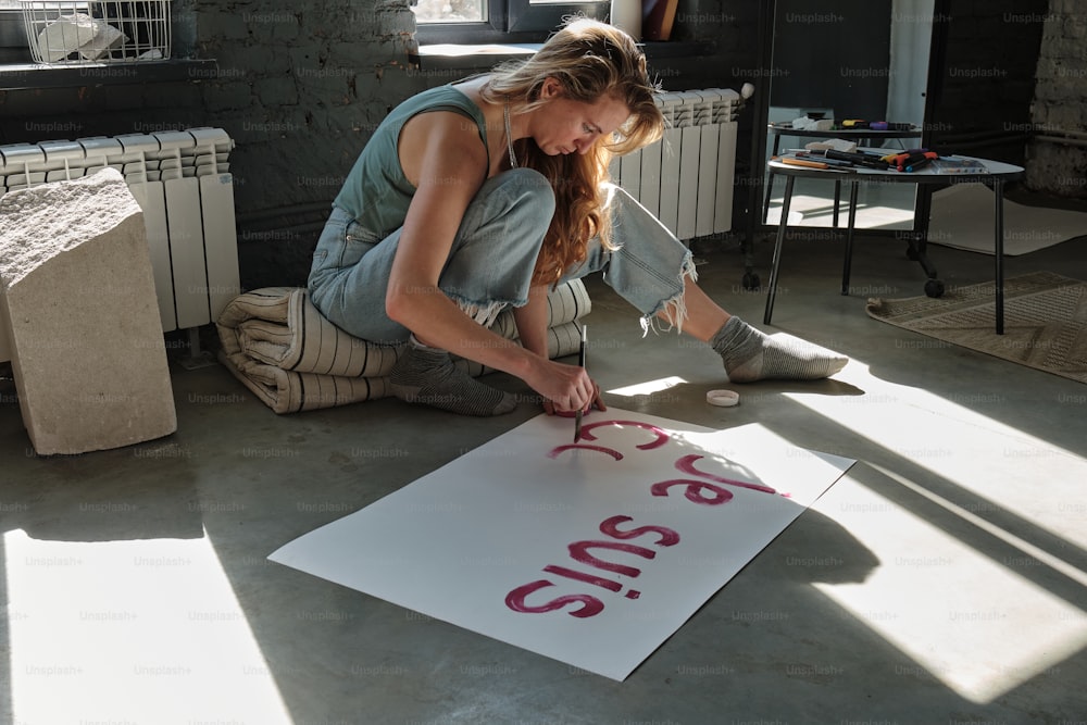a woman is sitting on the floor with a sign