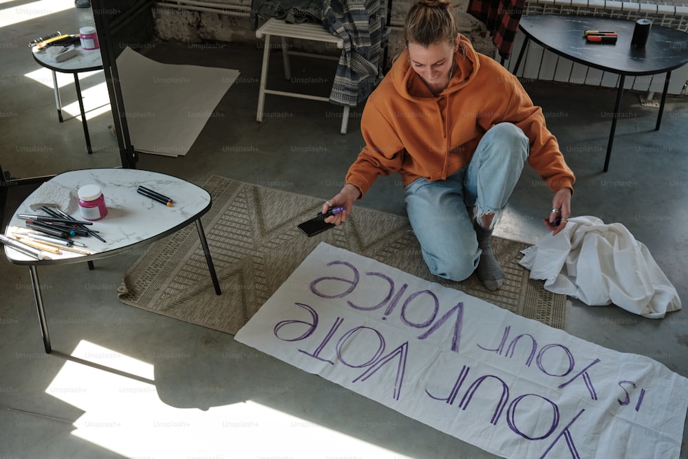 a woman sitting on the floor next to a sign